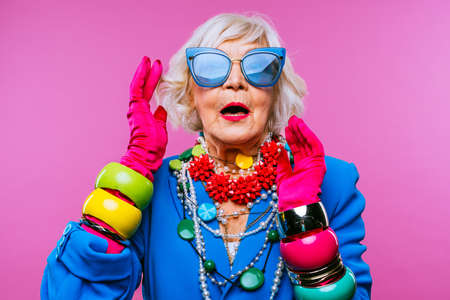 Happy and funny cool old lady with fashionable clothes portrait on colored background - Youthful grandmother with extravagant style, concepts about lifestyle, seniority and elderly peopleの写真素材