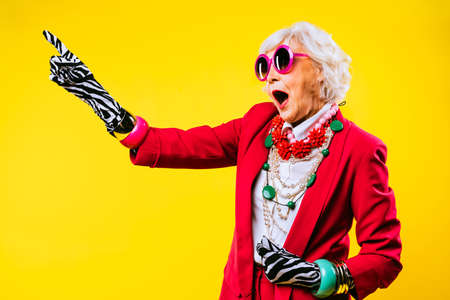 Happy and funny cool old lady with fashionable clothes portrait on colored background - Youthful...