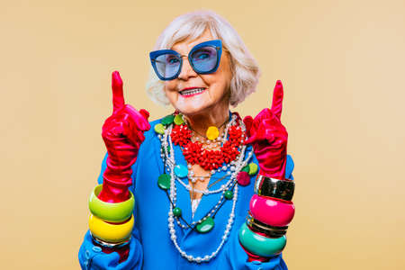 Happy and funny cool old lady with fashionable clothes portrait on colored background - Youthful...