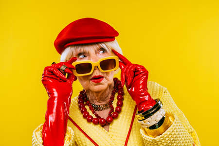 Happy and funny cool old lady with fashionable clothes portrait on colored background - Youthful grandmother with extravagant style, concepts about lifestyle, seniority and elderly peopleの写真素材