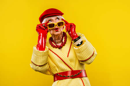 Happy and funny cool old lady with fashionable clothes portrait on colored background - Youthful...