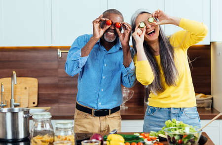 cinematic image of a multiethnic senior couple preparing food in the kitchen. Indoors Lifestyle...