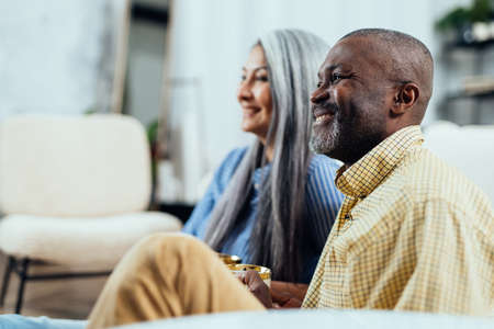 cinematic image of a multiethnic senior couple. Indoors Lifestyle moments at home. Concept about seniority and relationshipsの写真素材