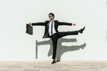 Happy and handsome adult businessman wearing elegant suit doing acrobatic trick moves in the city, alternative concept for business advertisement with energetic and creative peopleの写真素材