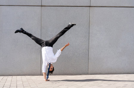 Happy and handsome adult businessman wearing elegant suit doing acrobatic trick moves in the city,...