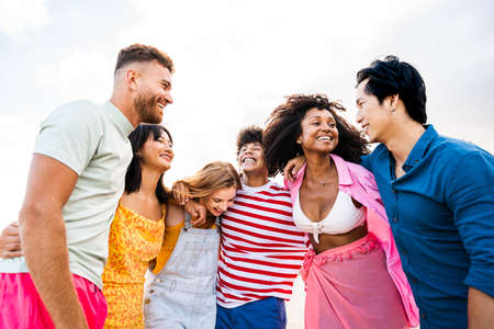 Multiethnic group of young happy friends bonding outside, having fun on summertime vacation - Multicultural cheerful people with summer clothes enjoying summer holidays, concepts about youth, friendship and positive emotionの写真素材