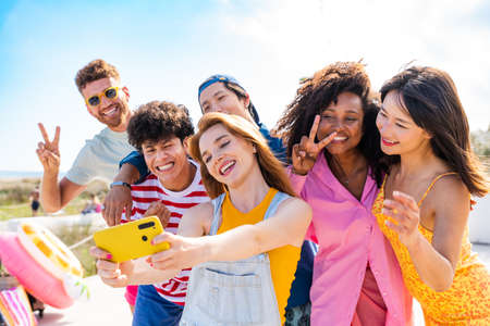 Multiethnic group of young happy friends bonding outside, having fun on summertime vacation -...