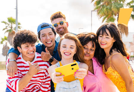 Multiethnic group of young happy friends bonding outside, having fun on summertime vacation - Multicultural cheerful people with summer clothes enjoying summer holidays, concepts about youth, friendship and positive emotionの写真素材