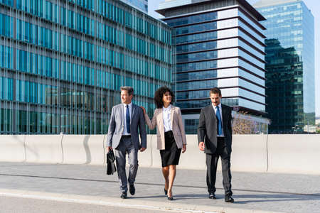 Multiracial group of business people bonding outdoors - International business corporate team wearing elegant suit meeting in a business parkの写真素材