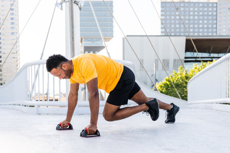 Black hispanic sportsman training outdoors in the city - African man with fit muscular body doing functional workout to train cardio, body muscles and abs coreの写真素材