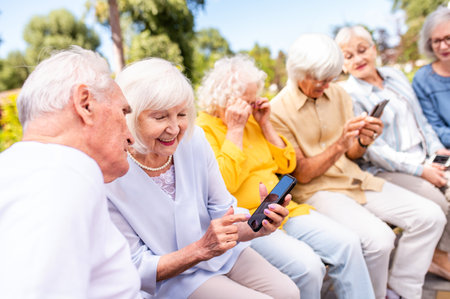 Group of happy elderly people bonding outdoors at the park - Old people in the age of 60, 70, 80 having fun and spending time together, concepts about elderly, seniority and wellness agingの写真素材