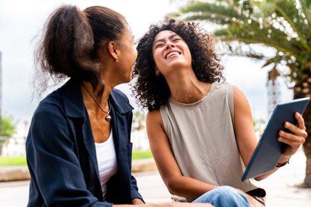 Happy beautiful hispanic south american women meeting outdoors and having fun - Black adult females friends spending time togetherの写真素材