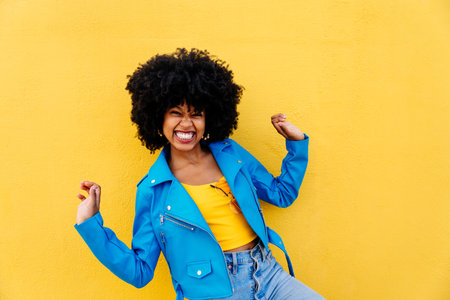Beautiful young happy african woman with afro curly hairstyle strolling in the city - Cheerful black...