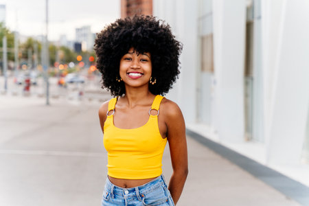 Beautiful young happy african woman with afro curly hairstyle strolling in the city - Cheerful black...