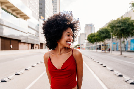 Beautiful young happy african woman with afro curly hairstyle strolling in the city - Cheerful black student walking on the streetsの写真素材