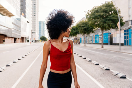 Beautiful young happy african woman with afro curly hairstyle strolling in the city - Cheerful black student walking on the streetsの写真素材