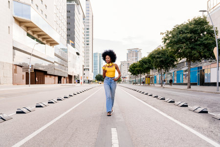 Beautiful young happy african woman with afro curly hairstyle strolling in the city - Cheerful black...