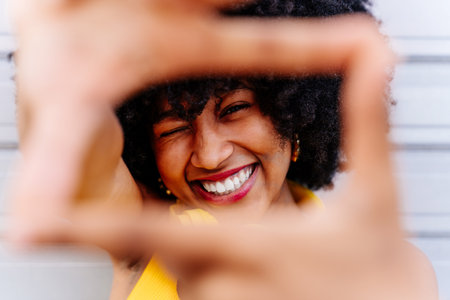 Beautiful young happy african woman with afro curly hairstyle strolling in the city - Cheerful black student portrait on colorful wall backgroundの写真素材
