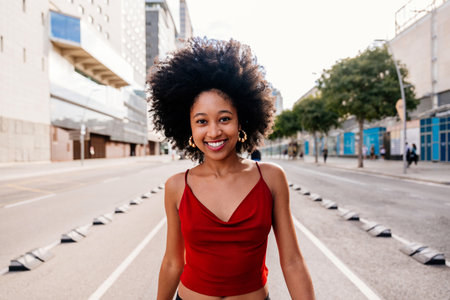 Beautiful young happy african woman with afro curly hairstyle strolling in the city - Cheerful black student walking on the streetsの写真素材
