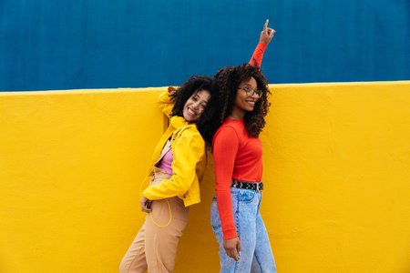 Young happy women dancing and having fun outdoors. Teenagers listening to music with smartphones and...