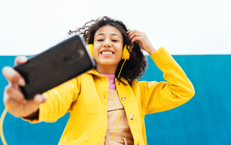young happy woman taking selfies and having fun outdoors. Teenager listening to music with...