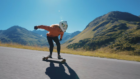 Cinematic downhill longboard session. Young woman skateboarding and making tricks between the curves on a mountain pass. Concept about extreme sports and peopleの写真素材