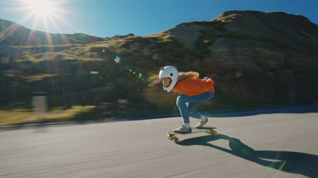 Cinematic downhill longboard session. Young woman skateboarding and making tricks between the curves on a mountain pass. Concept about extreme sports and peopleの写真素材
