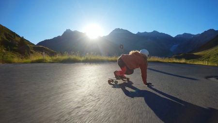 Cinematic downhill longboard session. Young woman skateboarding and making tricks between the curves on a mountain pass. Concept about extreme sports and peopleの写真素材