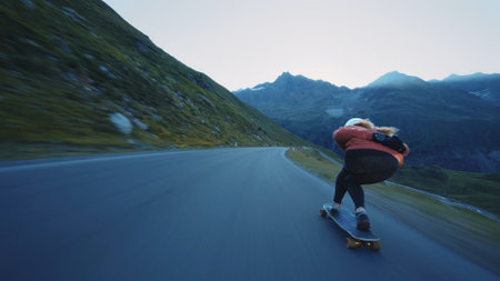 Cinematic downhill longboard session. Young woman skateboarding and making tricks between the curves on a mountain pass. Concept about extreme sports and peopleの写真素材