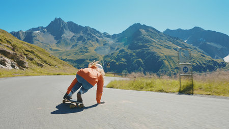 Cinematic downhill longboard session. Young woman skateboarding and making tricks between the curves on a mountain pass. Concept about extreme sports and peopleの写真素材
