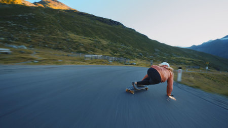 Cinematic downhill longboard session. Young woman skateboarding and making tricks between the curves on a mountain pass. Concept about extreme sports and peopleの写真素材