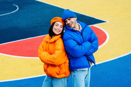 Multiracial young couple of lovers dating outdoors in winter, wearing winter jackets and having fun - Multiethnic millennials bonding in an urban area, concepts about youth and social releationshipsの写真素材