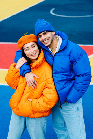 Multiracial young couple of lovers dating outdoors in winter, wearing winter jackets and having fun - Multiethnic millennials bonding in an urban area, concepts about youth and social releationshipsの写真素材