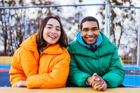 Multiracial young couple of lovers dating outdoors in winter, wearing winter jackets and having fun - Multiethnic millennials bonding in an urban area, concepts about youth and social releationshipsの写真素材