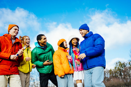 Multiracial group of young happy friends meeting outdoors in winter and celebrating party with confetti shooter, wearing winter jackets and having fun - Multiethnic millennials bonding in a urban area, concepts about youth and social releationshipsの写真素材