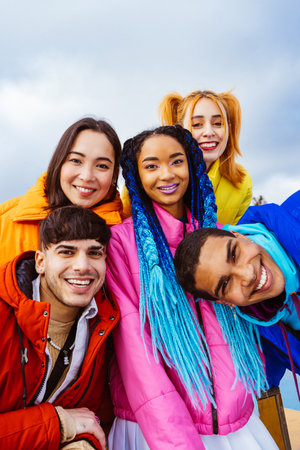 Multiracial group of young happy friends meeting outdoors in winter, wearing winter jackets and having fun - Multiethnic millennials bonding in an urban area, concepts about youth and social releationshipsの写真素材