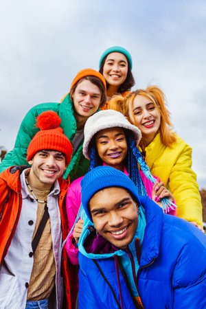 Multiracial group of young happy friends meeting outdoors in winter, wearing winter jackets and having fun - Multiethnic millennials bonding in an urban area, concepts about youth and social releationshipsの写真素材