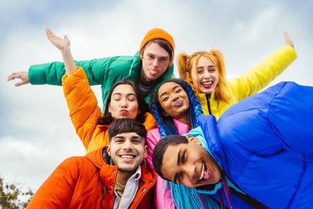 Multiracial group of young happy friends meeting outdoors in winter, wearing winter jackets and having fun - Multiethnic millennials bonding in an urban area, concepts about youth and social releationshipsの写真素材