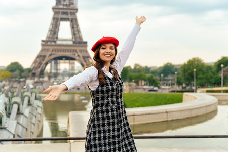 Beautiful young woman visiting paris and the eiffel tower. Parisian girl with red hat and fashionable clothes having fun in the city center and landmarks areaの写真素材