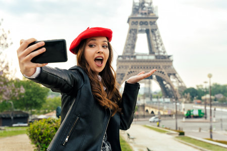 Beautiful young woman visiting paris and the eiffel tower. Parisian girl with red hat and fashionable clothes having fun in the city center and landmarks areaの写真素材