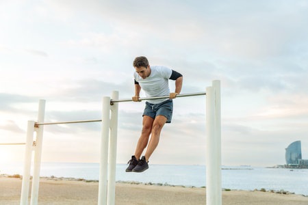 Sportive and athletic man doing functional training exercise at the outdoor gym - Adult athlete doing workout at sunrise at calisthenics park on the beach - Fitness, healthy lifestyle and sport conceptsの写真素材