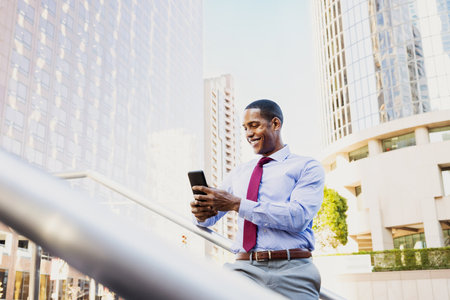 Handsome male african american business man CEO in a stylish corporate elegant suit in a business center outdoors - Black male commuter going to work, city and financial district in the backgroundの写真素材