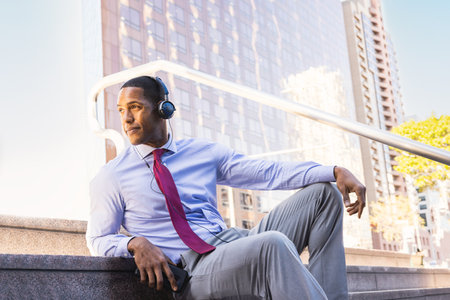 Handsome male african american business man CEO in a stylish corporate elegant suit in a business center outdoors - Black male commuter going to work, city and financial district in the backgroundの写真素材