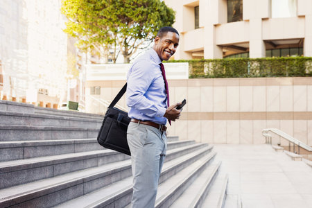 Handsome male african american business man CEO in a stylish corporate elegant suit in a business center outdoors - Black male commuter going to work, city and financial district in the backgroundの写真素材