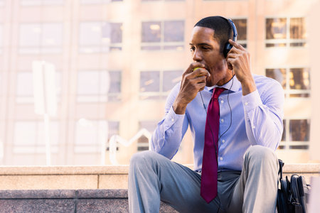 Handsome male african american business man CEO in a stylish corporate elegant suit in a business center outdoors - Black male commuter going to work, city and financial district in the backgroundの写真素材