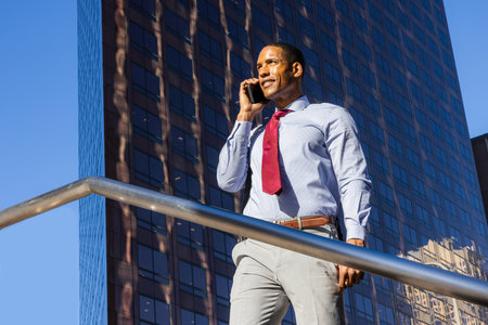 Handsome male african american business man CEO in a stylish corporate elegant suit in a business center outdoors - Black male commuter going to work, city and financial district in the backgroundの写真素材