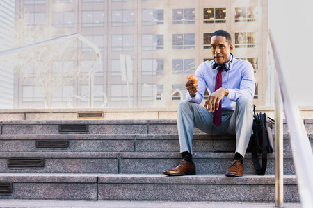 Handsome male african american business man CEO in a stylish corporate elegant suit in a business center outdoors - Black male commuter going to work, city and financial district in the backgroundの写真素材