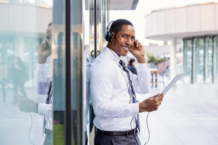 Handsome male african american business man CEO in a stylish corporate elegant suit in a business center outdoors - Black male commuter going to work, city and financial district in the backgroundの写真素材