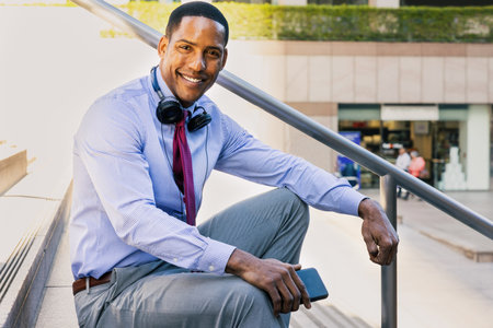 Handsome male african american business man CEO in a stylish corporate elegant suit in a business center outdoors - Black male commuter going to work, city and financial district in the backgroundの写真素材