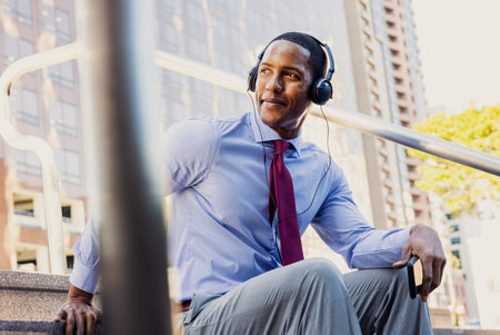 Handsome male african american business man CEO in a stylish corporate elegant suit in a business center outdoors - Black male commuter going to work, city and financial district in the backgroundの写真素材